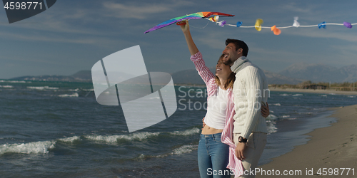 Image of Happy couple having fun with kite on beach