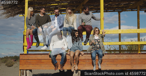 Image of Group of friends having fun on autumn day at beach