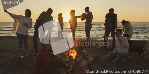 Image of Friends having fun at beach on autumn day