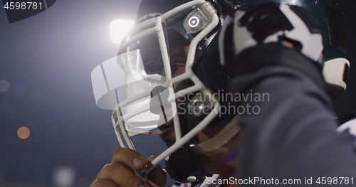 Image of American Football Player Putting On Helmet on large stadium with