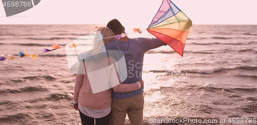 Image of Happy couple having fun with kite on beach