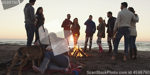 Image of Friends having fun at beach on autumn day