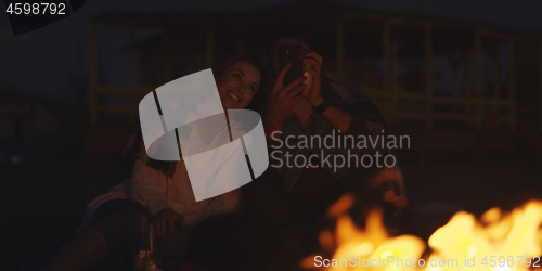 Image of Couple enjoying bonfire with friends on beach