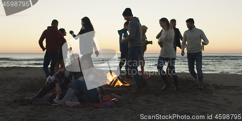 Image of Friends having fun at beach on autumn day