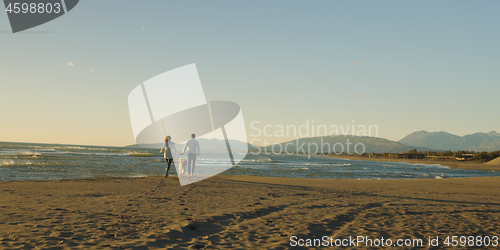 Image of couple with dog having fun on beach on autmun day