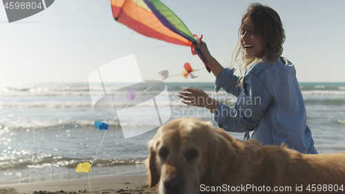 Image of Woman holding kite at beach on autumn day