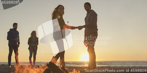 Image of Friends having fun at beach on autumn day