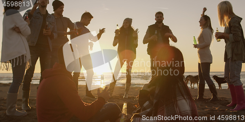 Image of Friends having fun at beach on autumn day