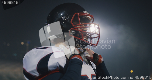 Image of American Football Player Putting On Helmet on large stadium with