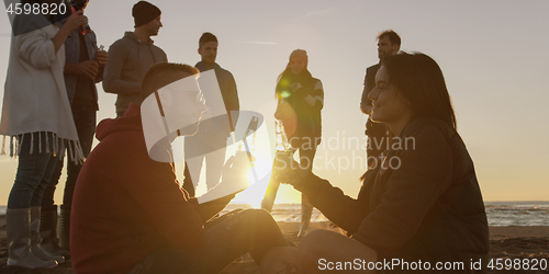 Image of Friends having fun at beach on autumn day