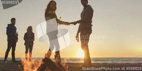 Image of Friends having fun at beach on autumn day