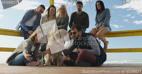 Image of Group of friends having fun on autumn day at beach