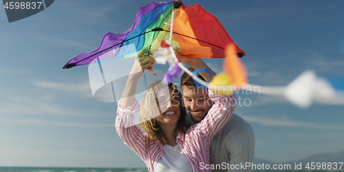 Image of Happy couple having fun with kite on beach