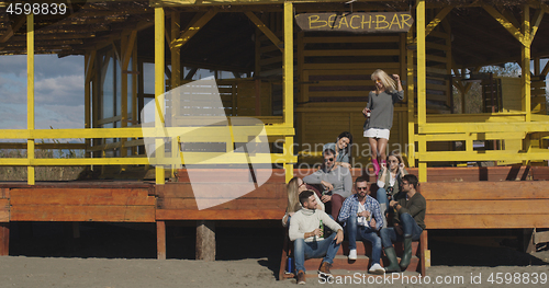 Image of Group of friends having fun on autumn day at beach