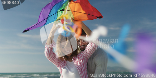 Image of Happy couple having fun with kite on beach