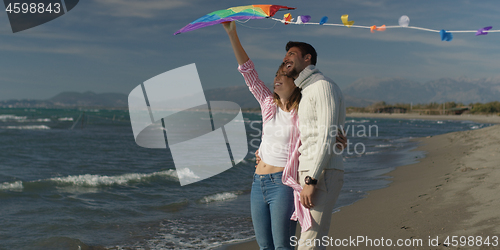 Image of Happy couple having fun with kite on beach