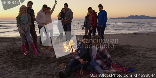 Image of Friends having fun at beach on autumn day