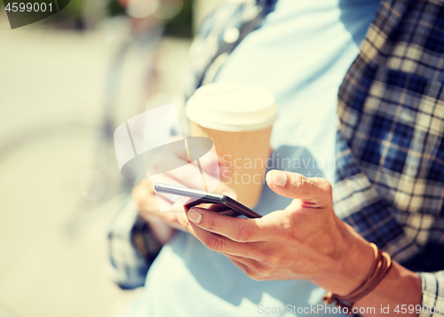 Image of man with smartphone and coffee on city street