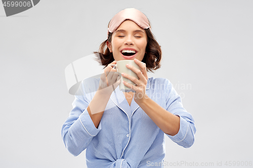 Image of woman in pajama and sleeping mask drinking coffee