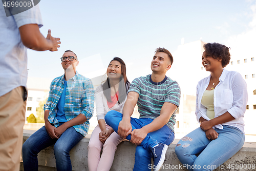 Image of happy international friends talking in city