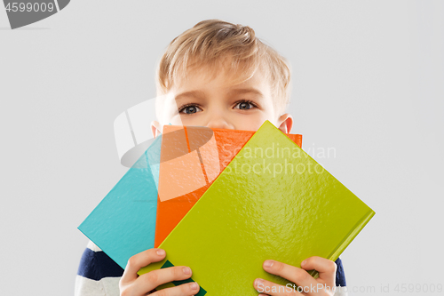 Image of shy schoolboy hiding behind books