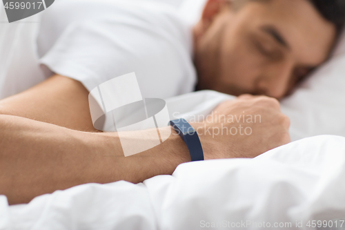 Image of close up of man sleeping with activity tracker