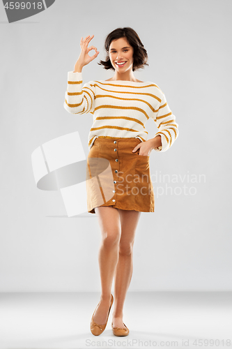 Image of woman in pullover, skirt and shoes showing ok