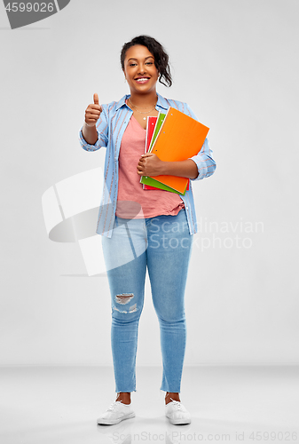 Image of african student with notebooks showing thumbs up