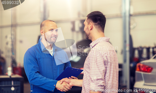 Image of auto mechanic and man shaking hands at car shop