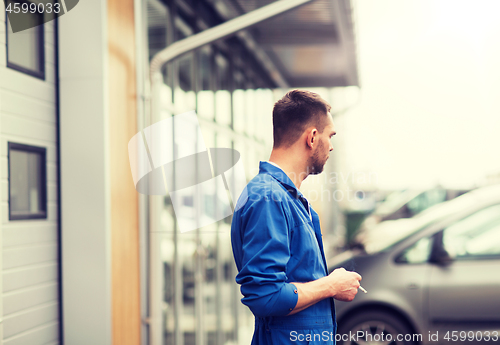 Image of auto mechanic smoking cigarette at car workshop