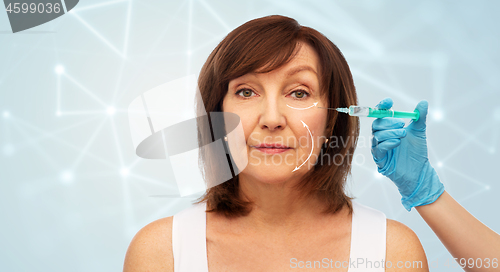 Image of senior woman and cosmetologist\'s hand with syringe