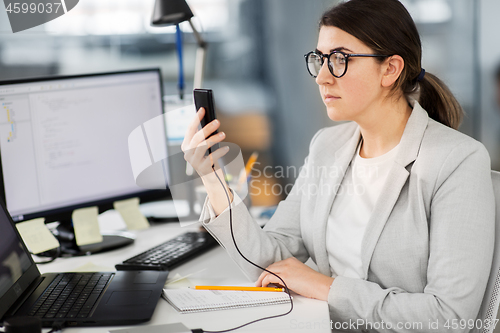 Image of businesswoman using smartphone at office