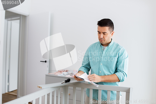 Image of father with manual assembling baby bed at home