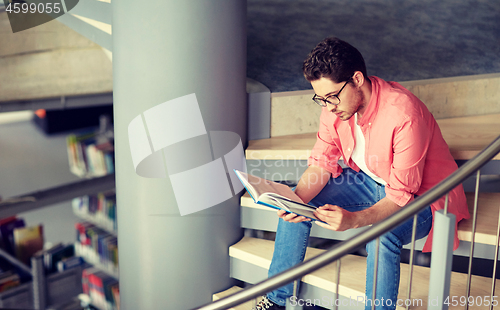 Image of student boy or young man reading book at library