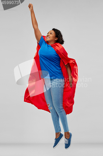 Image of african american woman in superhero cape flying up