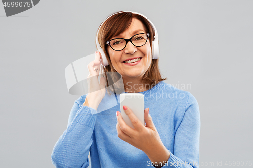 Image of senior woman in headphones listening music on cell
