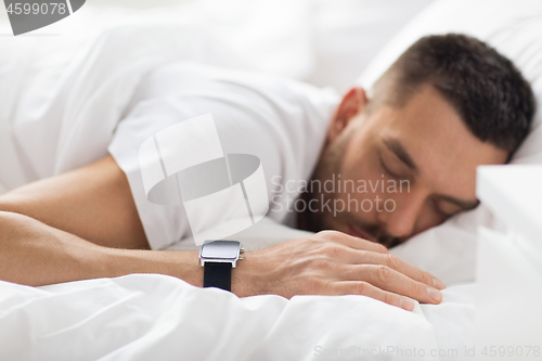 Image of close up of man with smart watch sleeping in bed