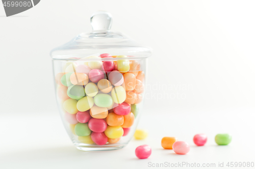 Image of glass jar with candy drops over white background