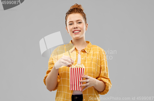 Image of smiling red haired teenage girl eating popcorn