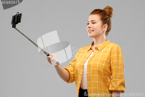 Image of happy teenage girl taking picture by selfie stick