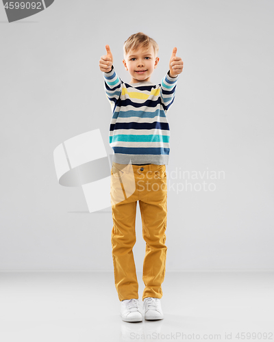 Image of smiling boy in striped pullover showing thumbs up