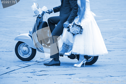 Image of Young newlywed just married, posing on an old scooter. Clas