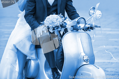 Image of Young newlywed just married, posing on an old  scooter. Clas