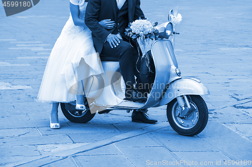 Image of Young newlywed just married, posing on an old scooter. Clas