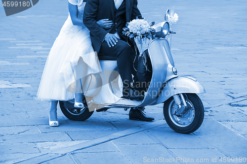 Image of Young newlywed just married, posing on an old scooter. Clas
