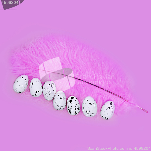 Image of Eggs on a pink feather on a pink background. Easter concept.