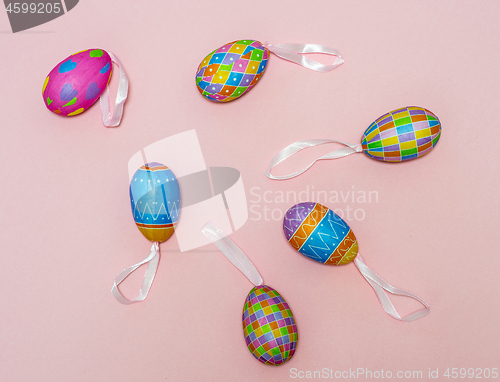 Image of Paper colorful Easter eggs lie on a gently pink background. Easter concept.