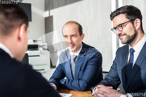 Image of Team of confident successful business people discussing the contract terms at business meeting in modern corporate office.