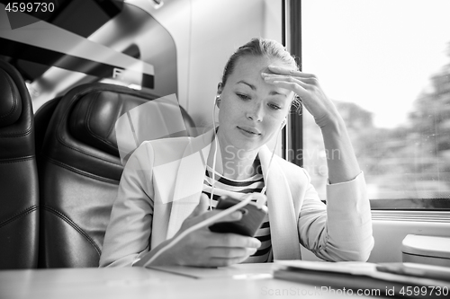 Image of Businesswoman communicating on mobile phone while traveling by train.