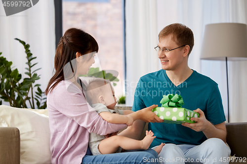 Image of mother with baby giving birthday present to father